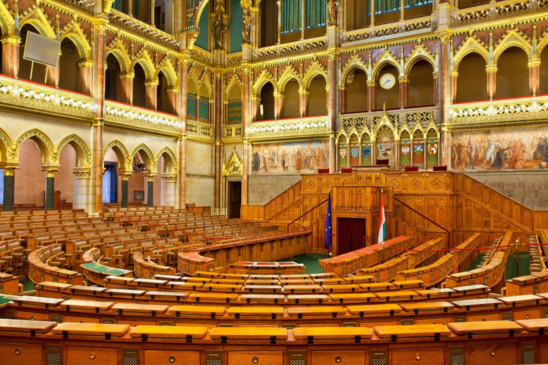Interior of the Hungarian Parliament building with ornate golden architecture and wooden seating.