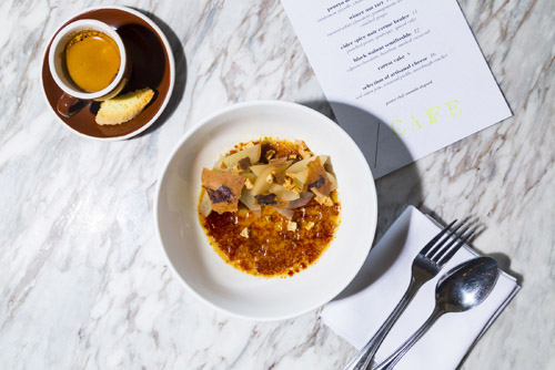 Plated dish at Lula Café in Logan Square with coffee and menu visible on marble table.