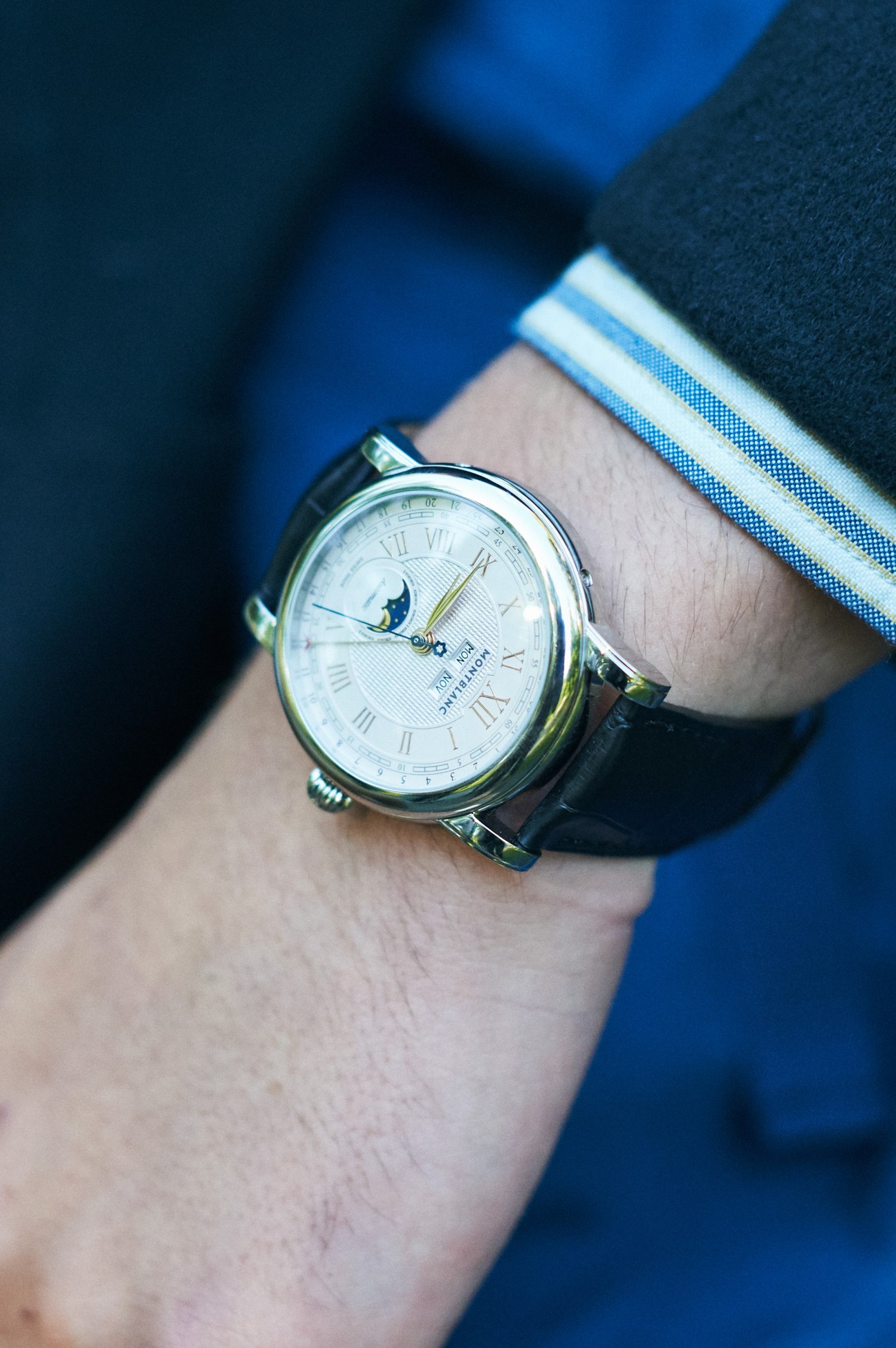 Close-up of Montblanc watch on wrist with white dial showing Roman numerals and moon phase
