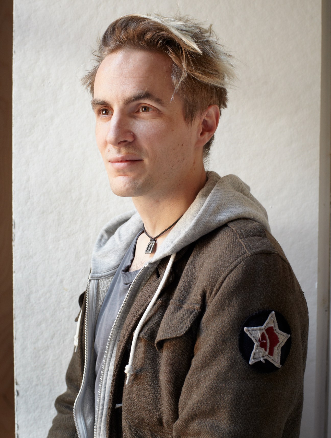 Portrait of Caspar Newbolt, co-founder of Version Industries, wearing a brown jacket with a red star patch.