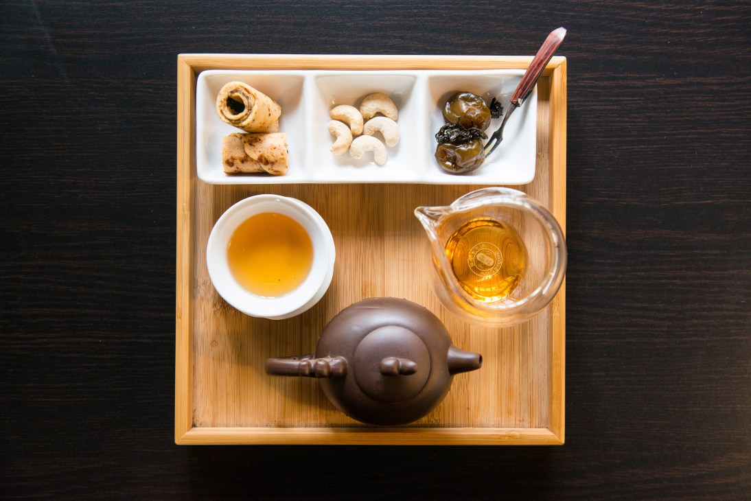 Japanese tea service arranged on wooden tray with teapot, cups, and traditional snacks.