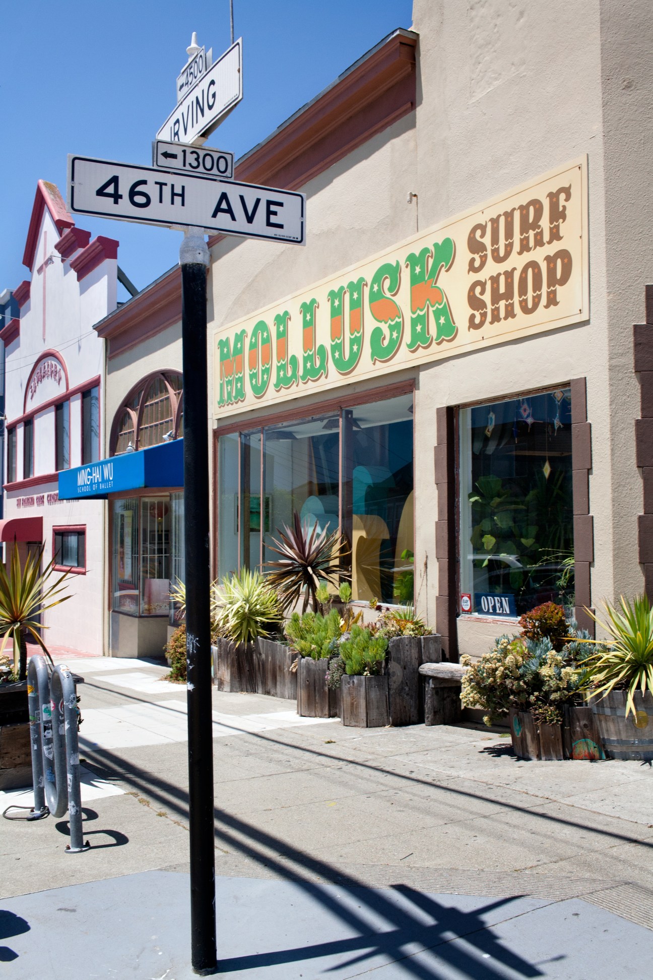 Mollusk Surf Shop storefront with hand-painted green and gold lettering sign on cream-colored building.
