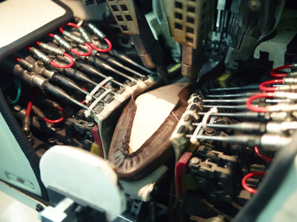Close-up of industrial textile printing equipment with red and black mechanical components and wooden spools.