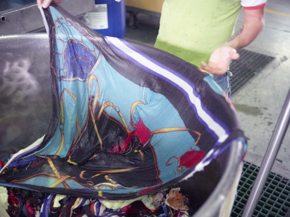 A worker holds a colorful silk fabric with floral patterns during production at a Como textile facility.