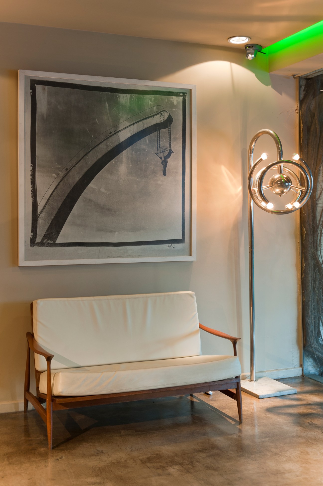 Mid-century modern lounge chair with cream cushions beside a sculptural brass floor lamp in a hotel interior