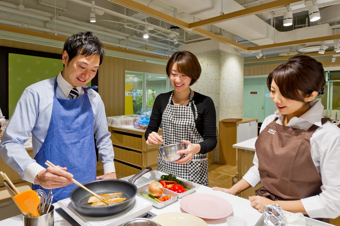 Students learning to cook in a kitchen classroom at ABC Cooking Studio in Tokyo.