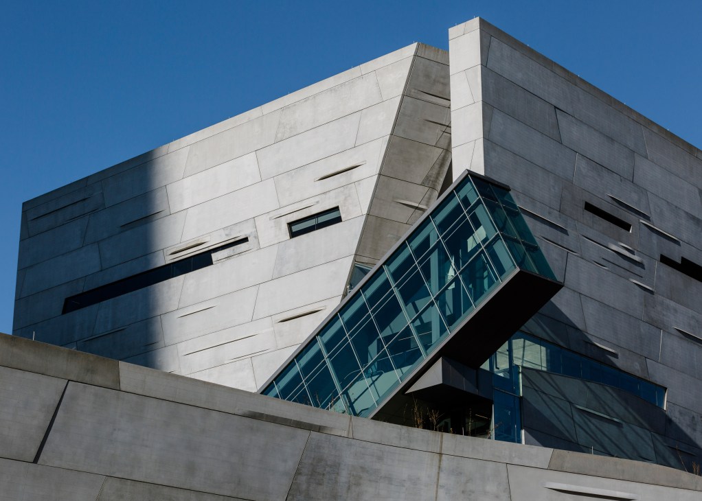 Modern concrete and glass museum building with angular architecture against clear blue sky.