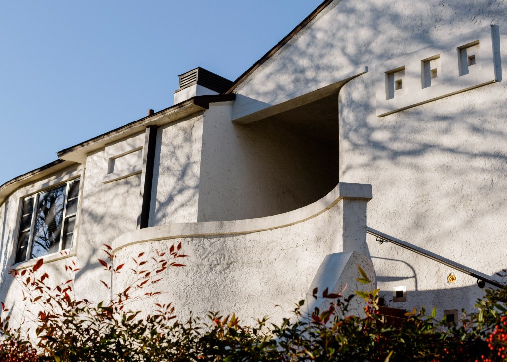 Belmont Hotel's white modernist facade with curved architectural details and large windows against a clear blue sky.