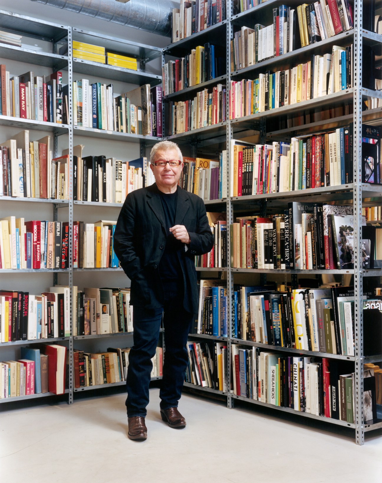 Daniel Libeskind stands before shelves of books in his office library.