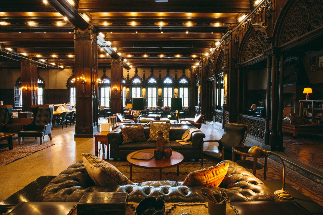 Ornate drawing room with high ceilings, decorative wooden columns, leather seating and warm lighting at Chicago Athletic Association.
