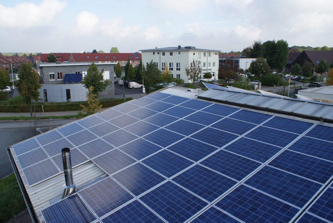 Solar panels installed on a rooftop in a German residential town, with houses visible in the background.