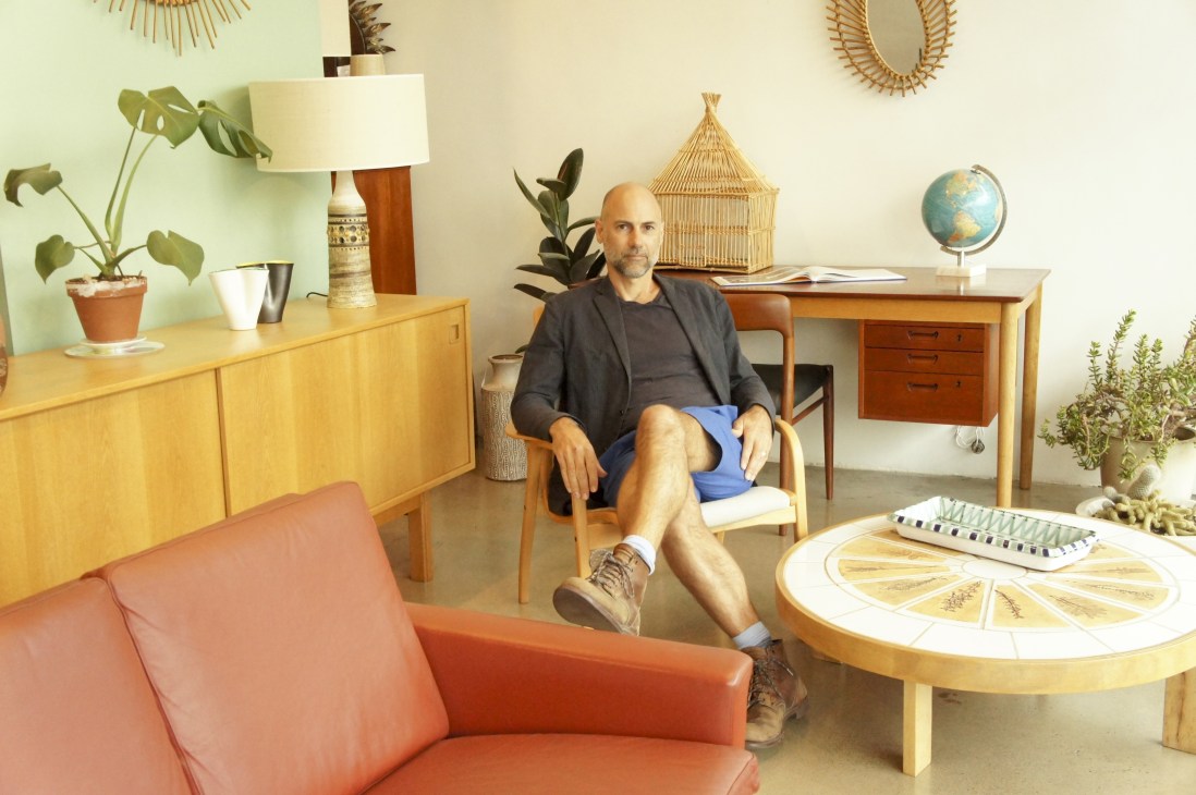 Fred Ganim sits in his studio surrounded by mid-century modern furniture and design objects.