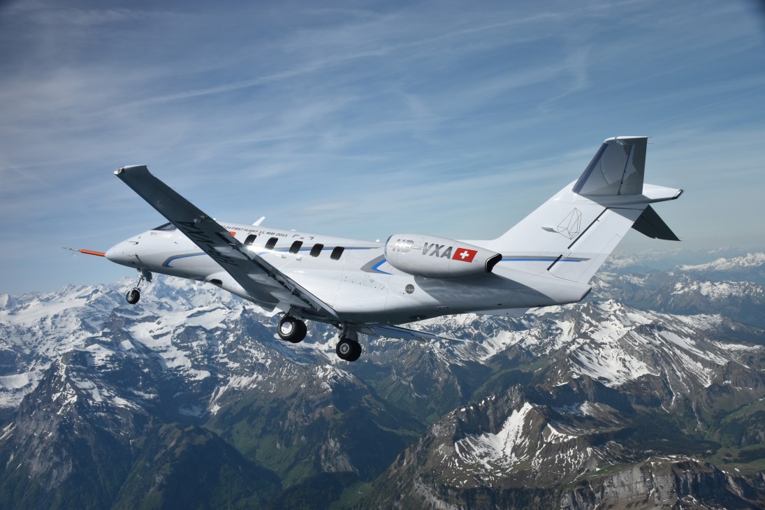 Swiss-registered aircraft HB-YXA flying over snowy Alpine mountains.