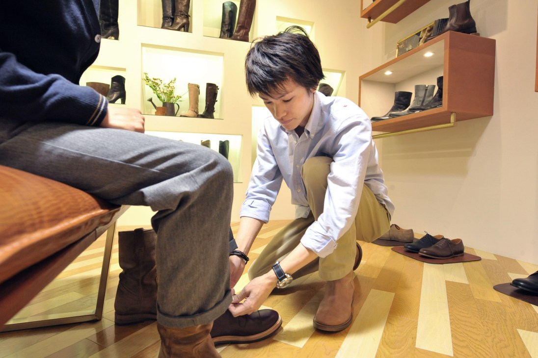 A salesman helps a customer try on boots at Antonia boutique in Milan.