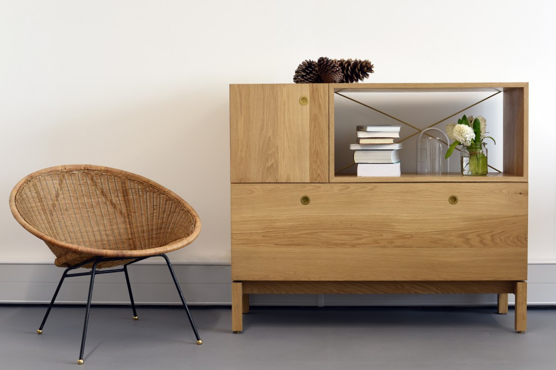 Beynon modular oak furniture unit with doors and drawers displayed with a rattan chair.