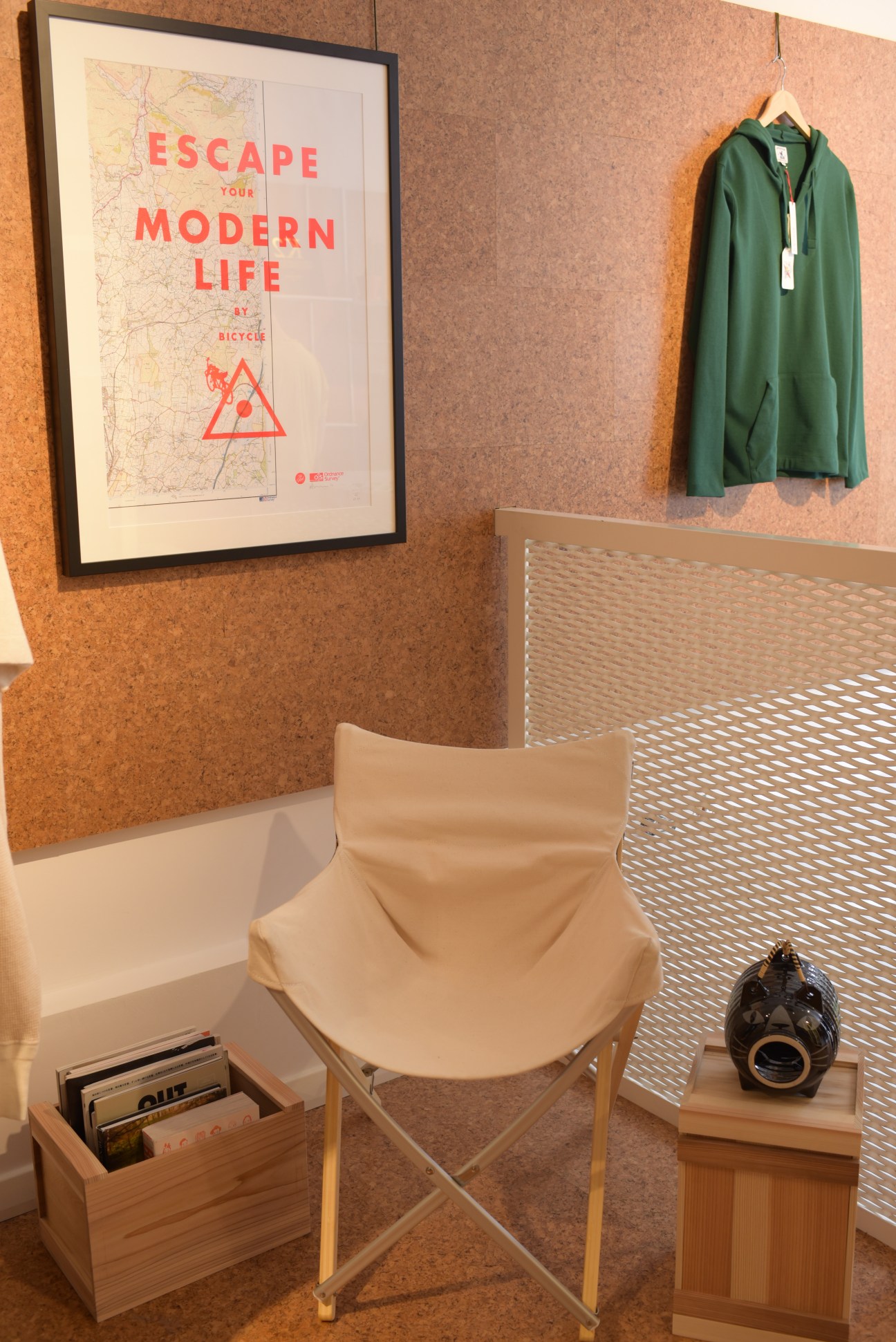 Kinoko shop interior displaying a green hooded jacket on a hanger against a cork wall with a framed bicycle poster.