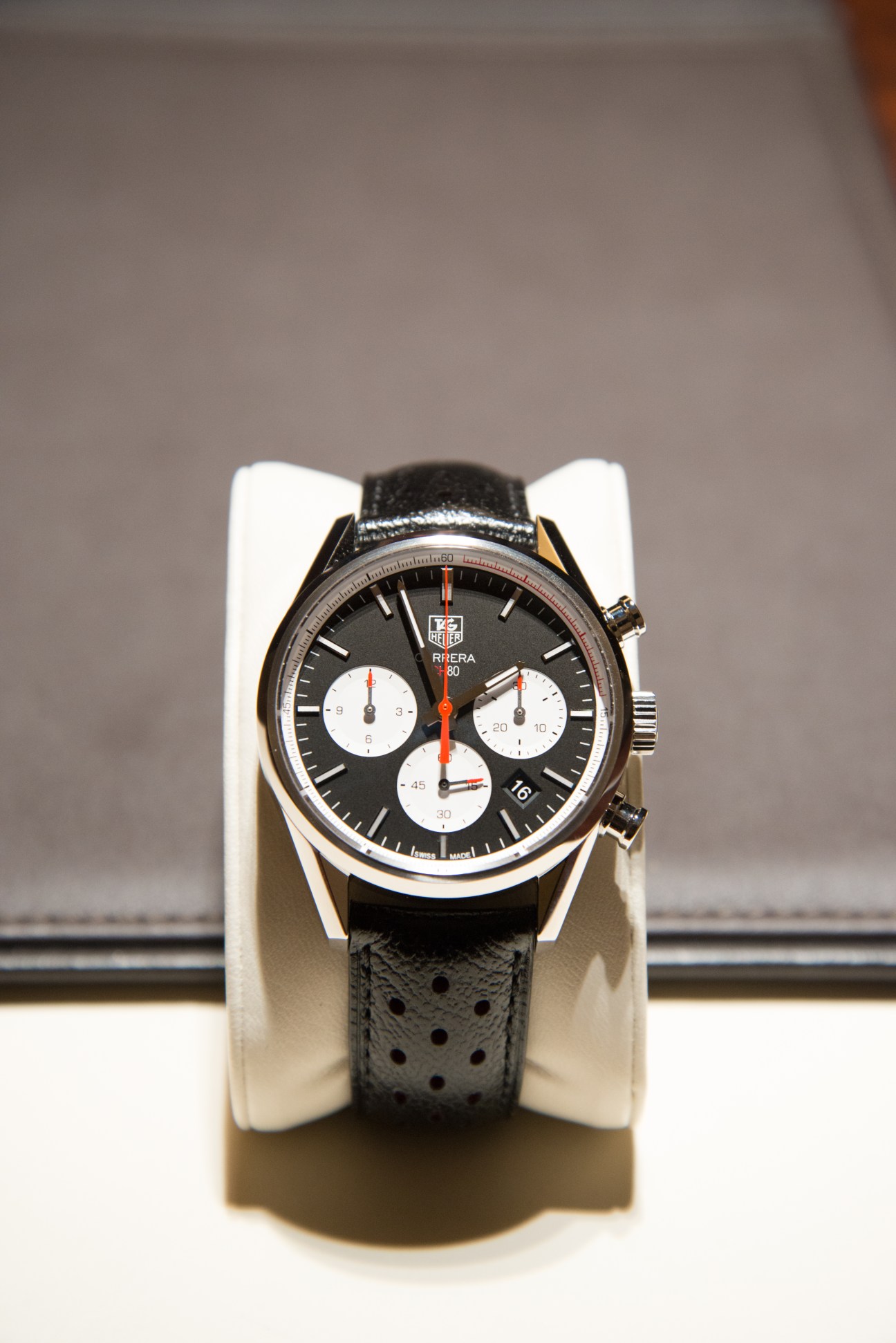Tag Heuer Carrera Calibre 80 Chronograph watch with black dial and leather strap on display stand.