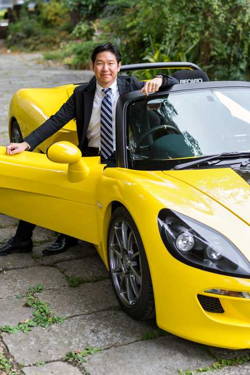 Man in business suit posing with bright yellow sports car
