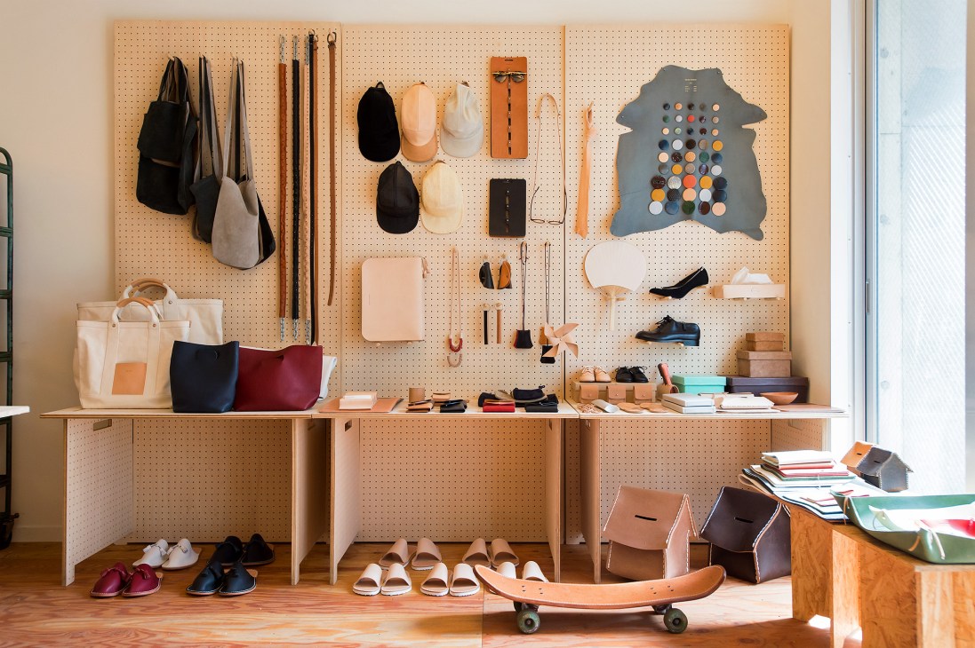 Jesse Kamm's studio display featuring organized clothing, accessories, shoes and design materials on pegboard.