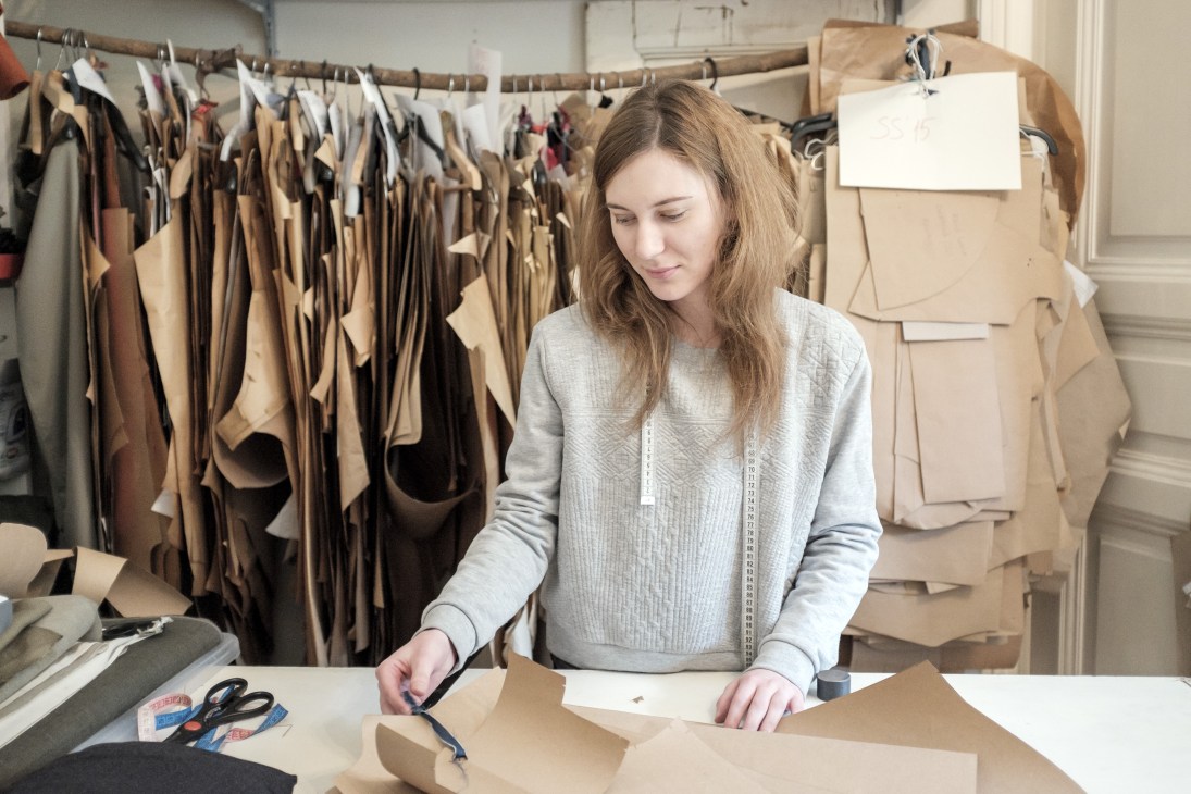 FlatLab assistant Zsuzsanna Tapolcai working at a desk with fabric samples hanging behind her.