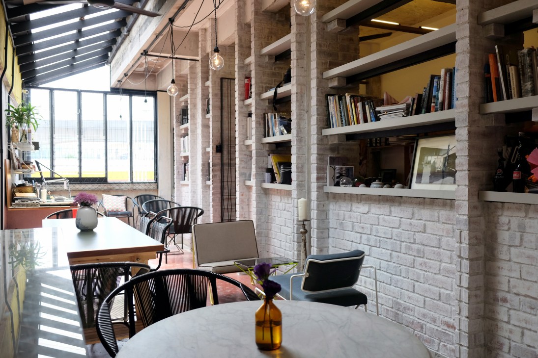 Modern loft interior with exposed brick, floating shelves, pendant lights, and contemporary furniture.