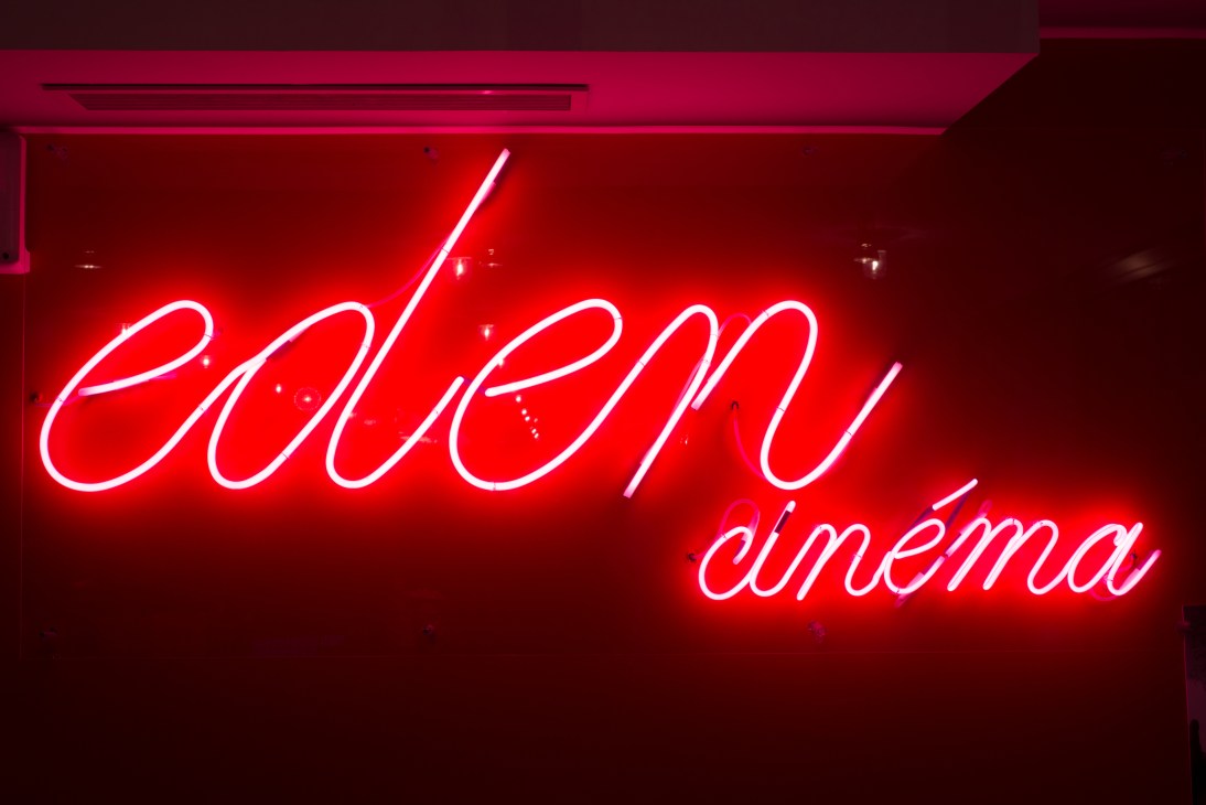 Red neon sign reading 'Eden cinema' against a dark background