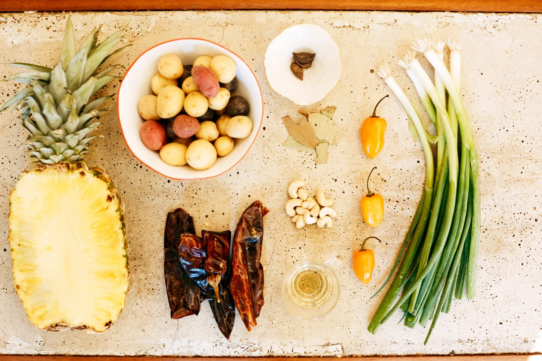 Ingredients for El Rey's fusion cuisine arranged on a speckled surface, including pineapple, potatoes, chilies, spring onions, cashews and spices.
