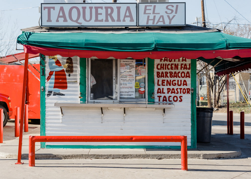 Taquería El Si Hay storefront with turquoise and red awning and signage advertising tacos and traditional Mexican dishes.