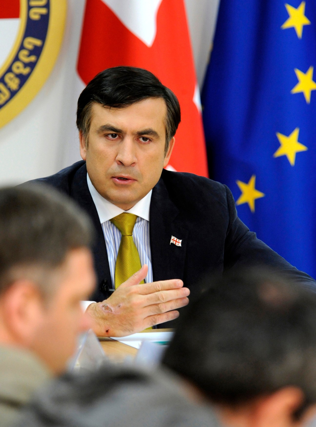 Georgian president Mikhail Saakashvili speaking at a press conference with EU and Georgian flags in the background.