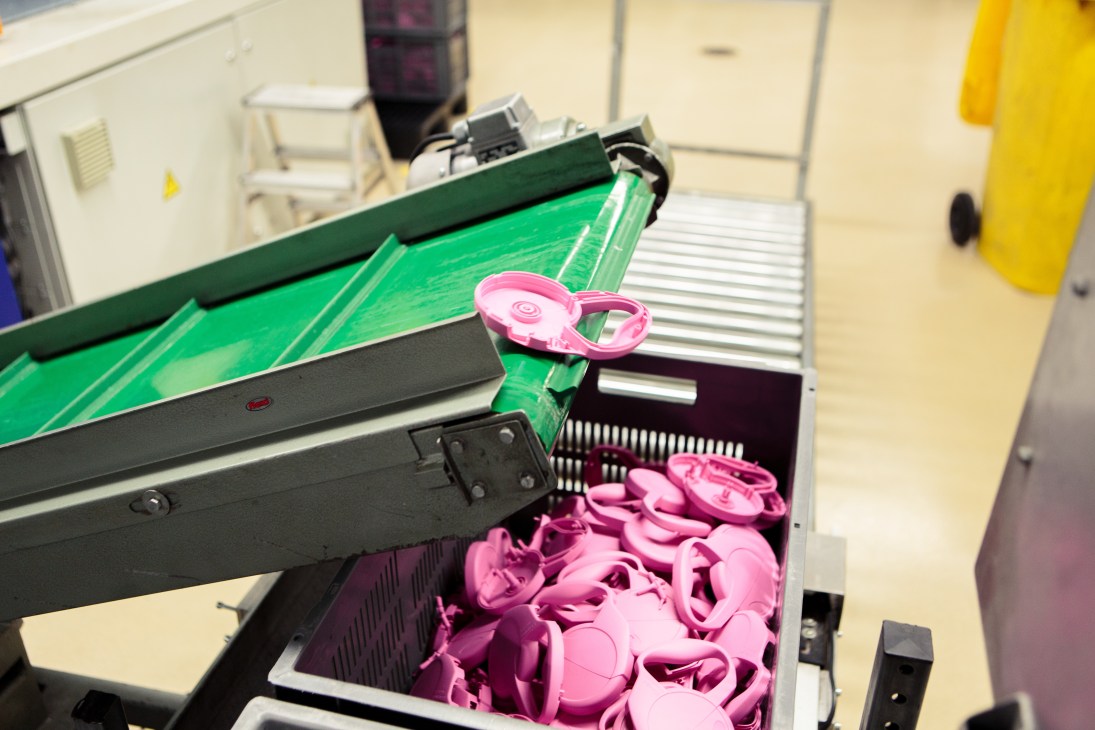 Pink retractable dog leads manufactured by Flexi on a production line with green machinery.