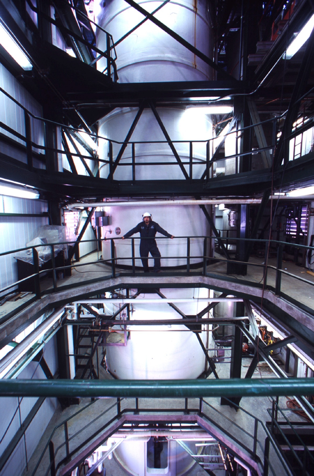 Worker standing on platform inside large cylindrical fermentation tank at Iogen biotech facility.