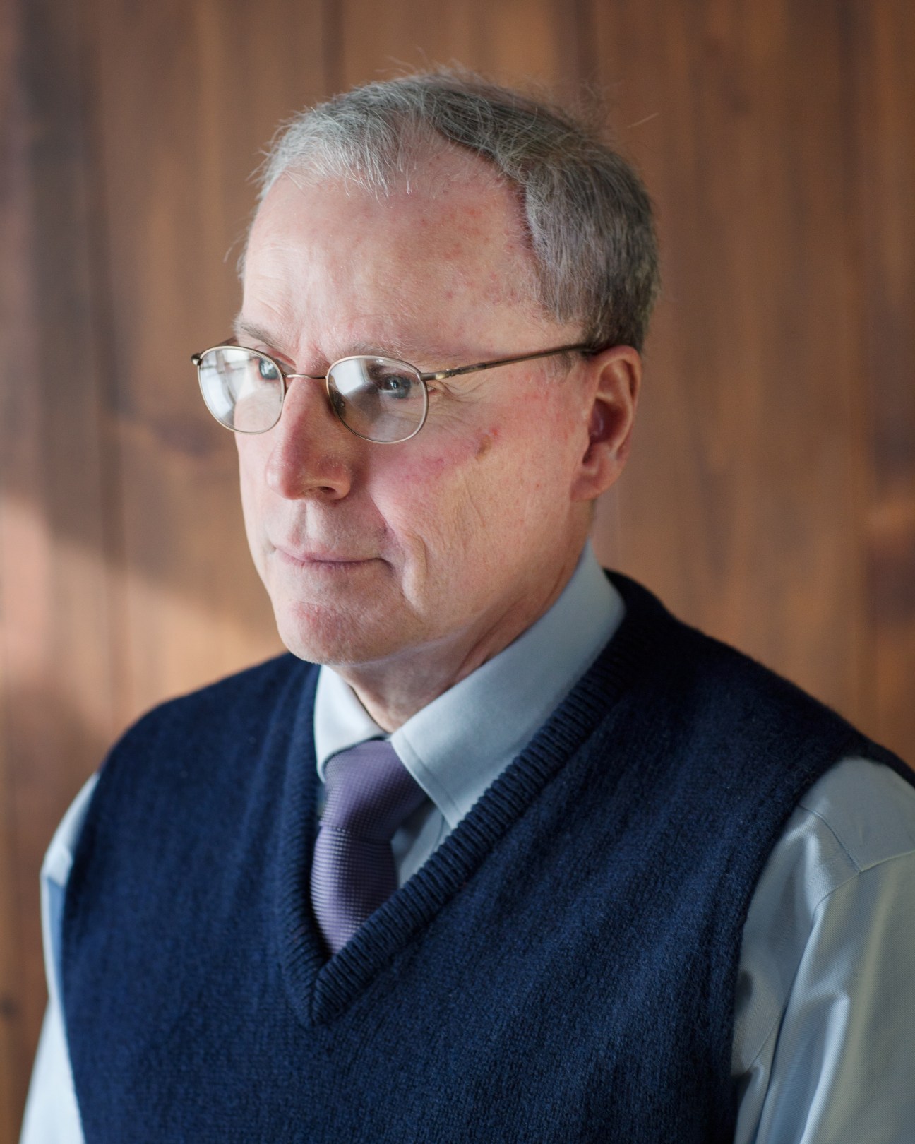Portrait of Robert S Ford, a man wearing glasses, light blue shirt, purple tie and dark navy vest.