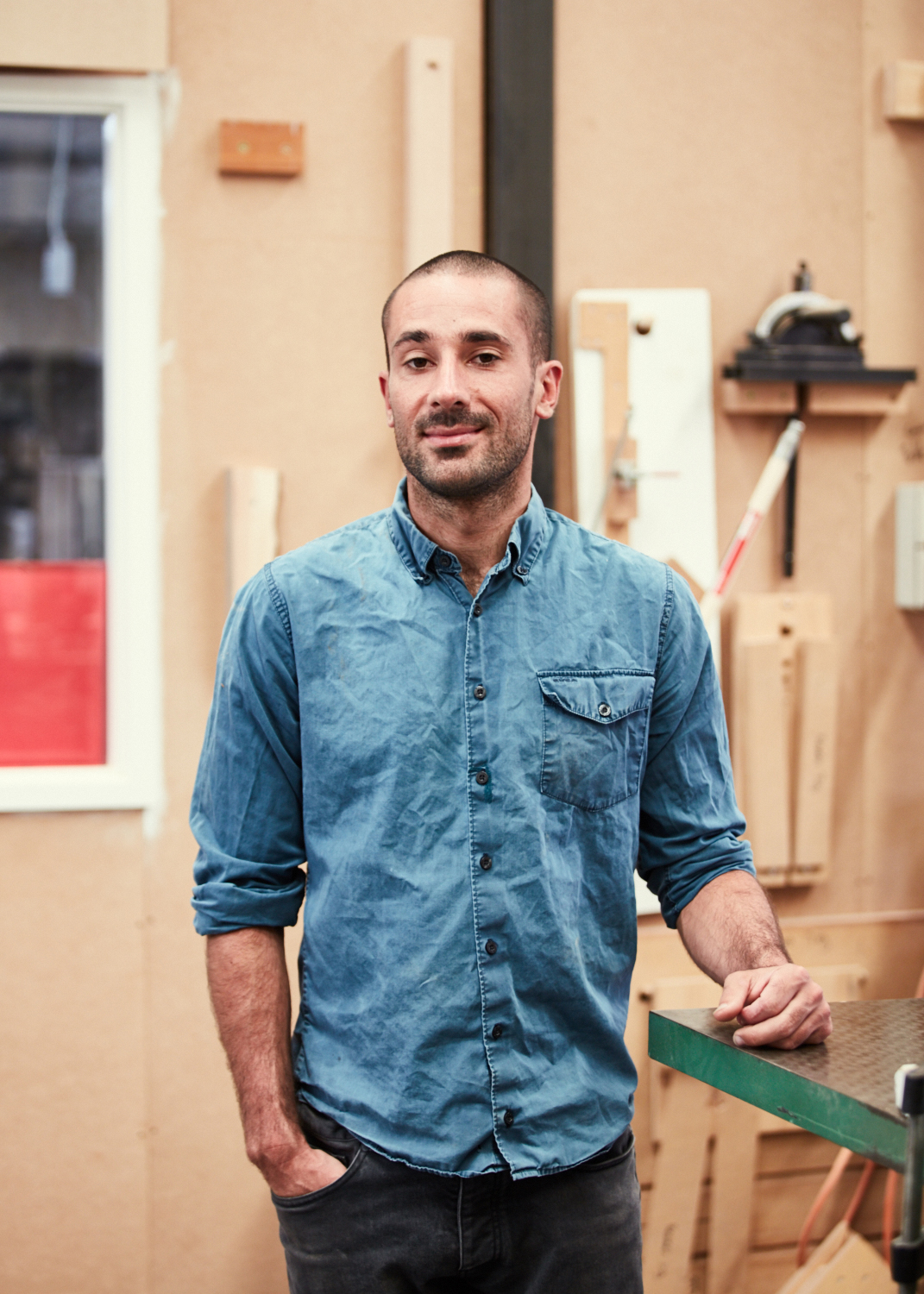 Fred Ganim, a furniture maker, stands in his Melbourne studio wearing a blue denim shirt.