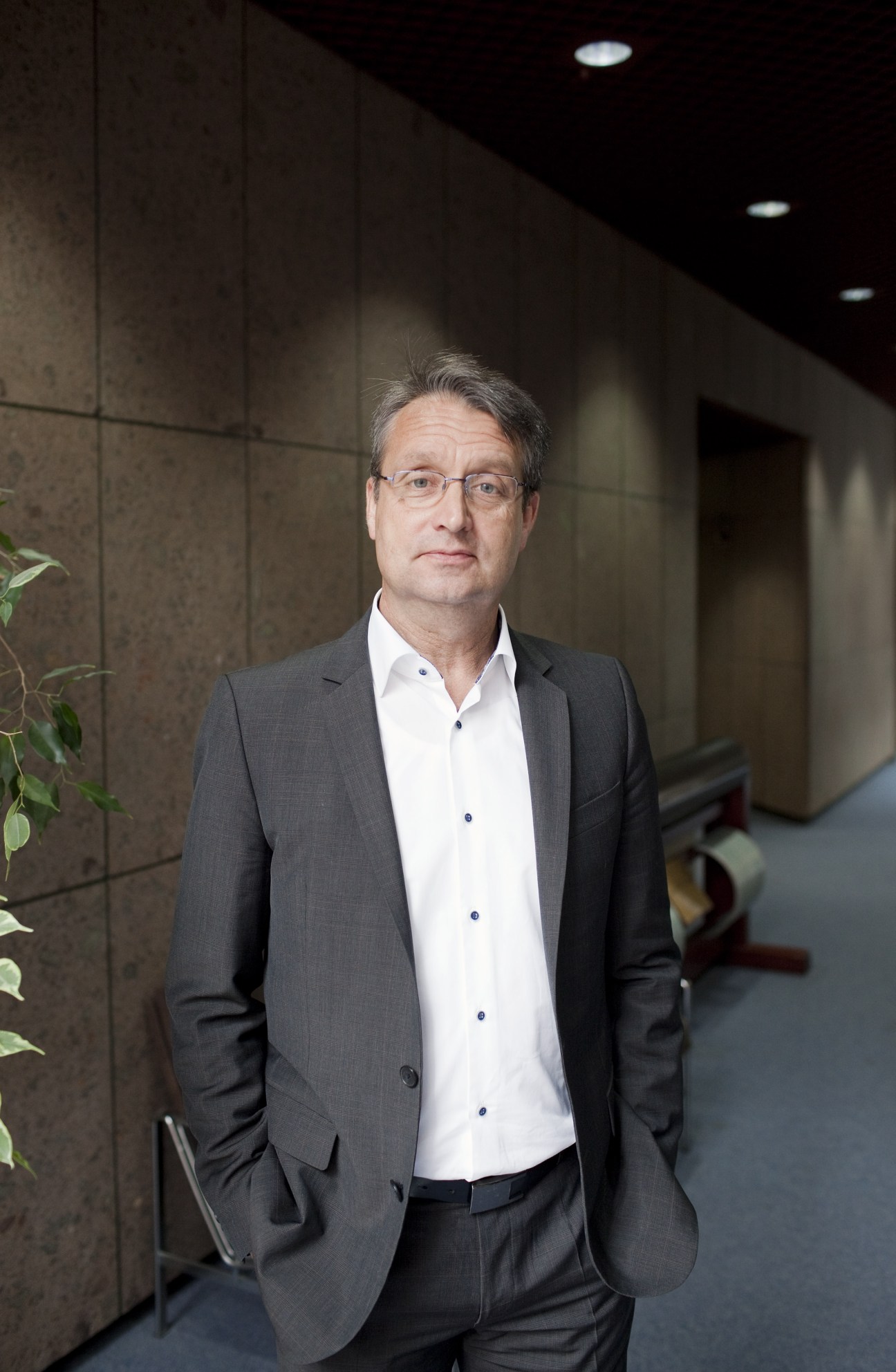 Gabor Steingart, newspaper editor, stands in a modern corridor wearing a grey blazer and white shirt.