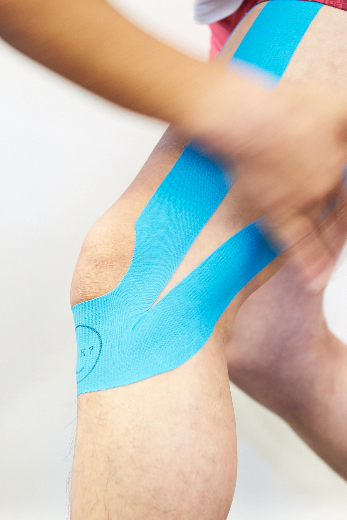 Close-up of bright blue athletic tape applied to a person's knee and leg.