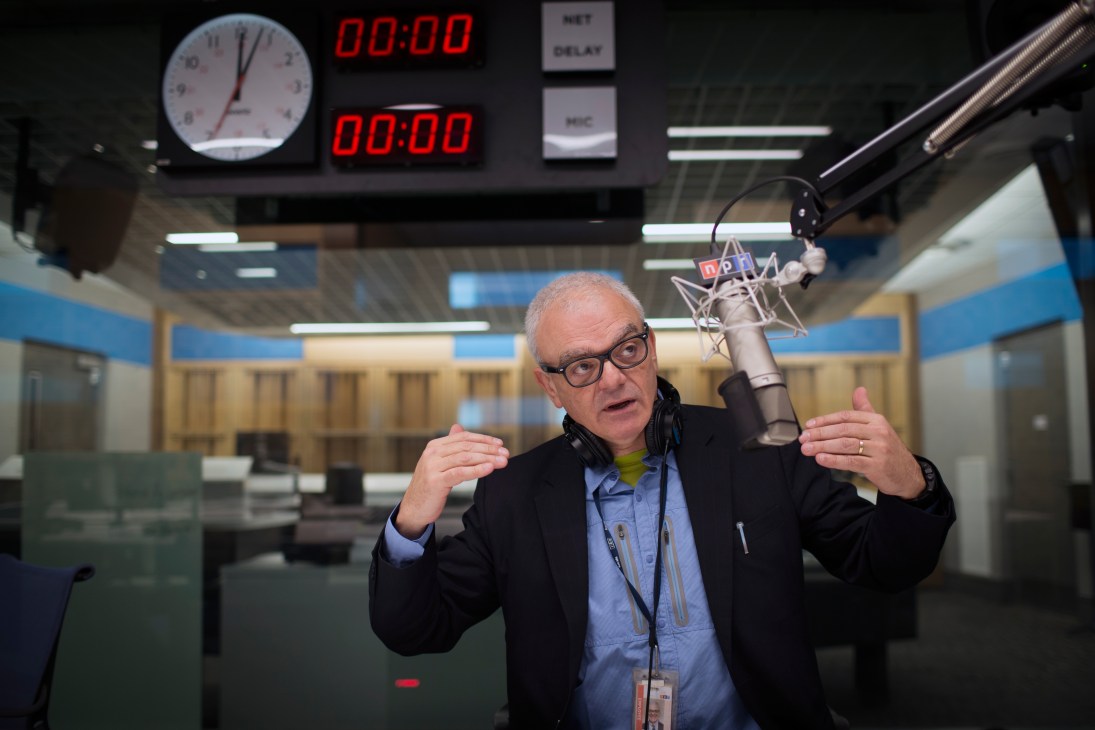 Don Gonyea speaks into a microphone in an NPR broadcast studio wearing headphones around his neck.