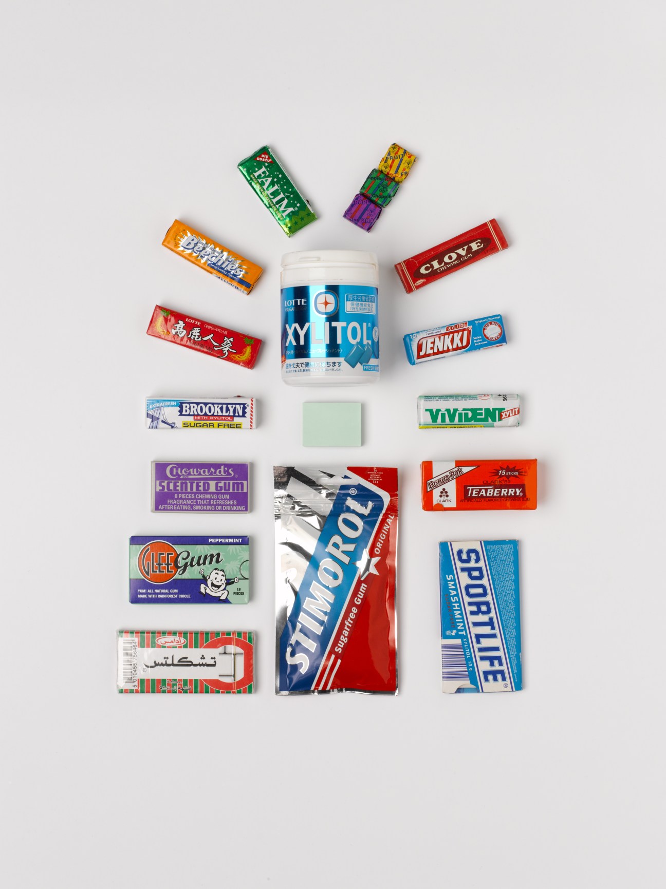 Collection of international chewing gum brands arranged around a white pot of Lotte Xylitol, including Glee Gum, Teaberry, Chiclets, and others.