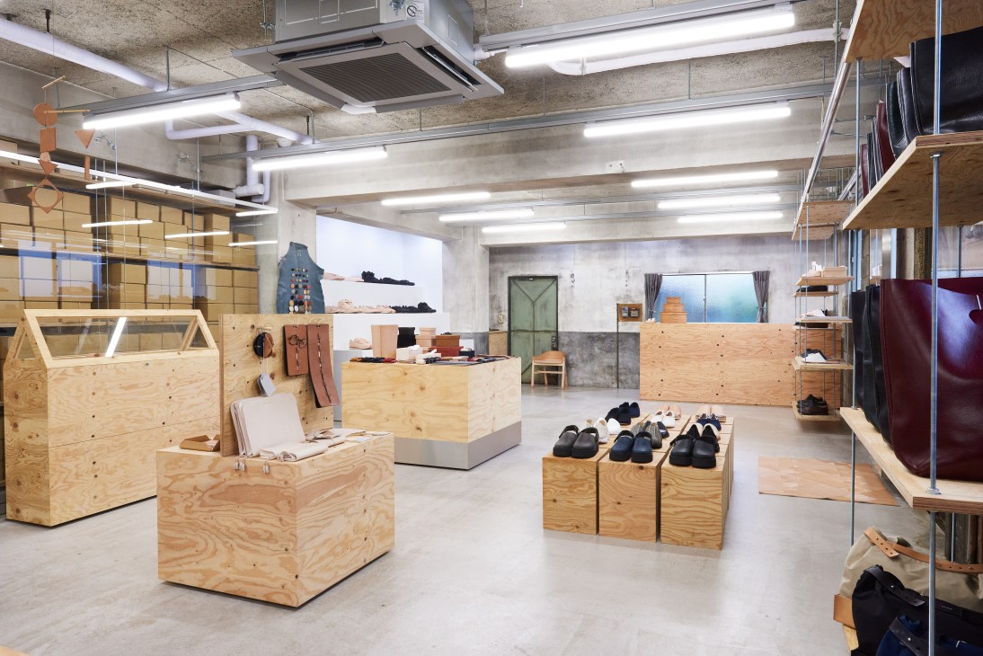 Interior of Skima shop in Tokyo displaying shoes and clothing on wooden display units and shelving.