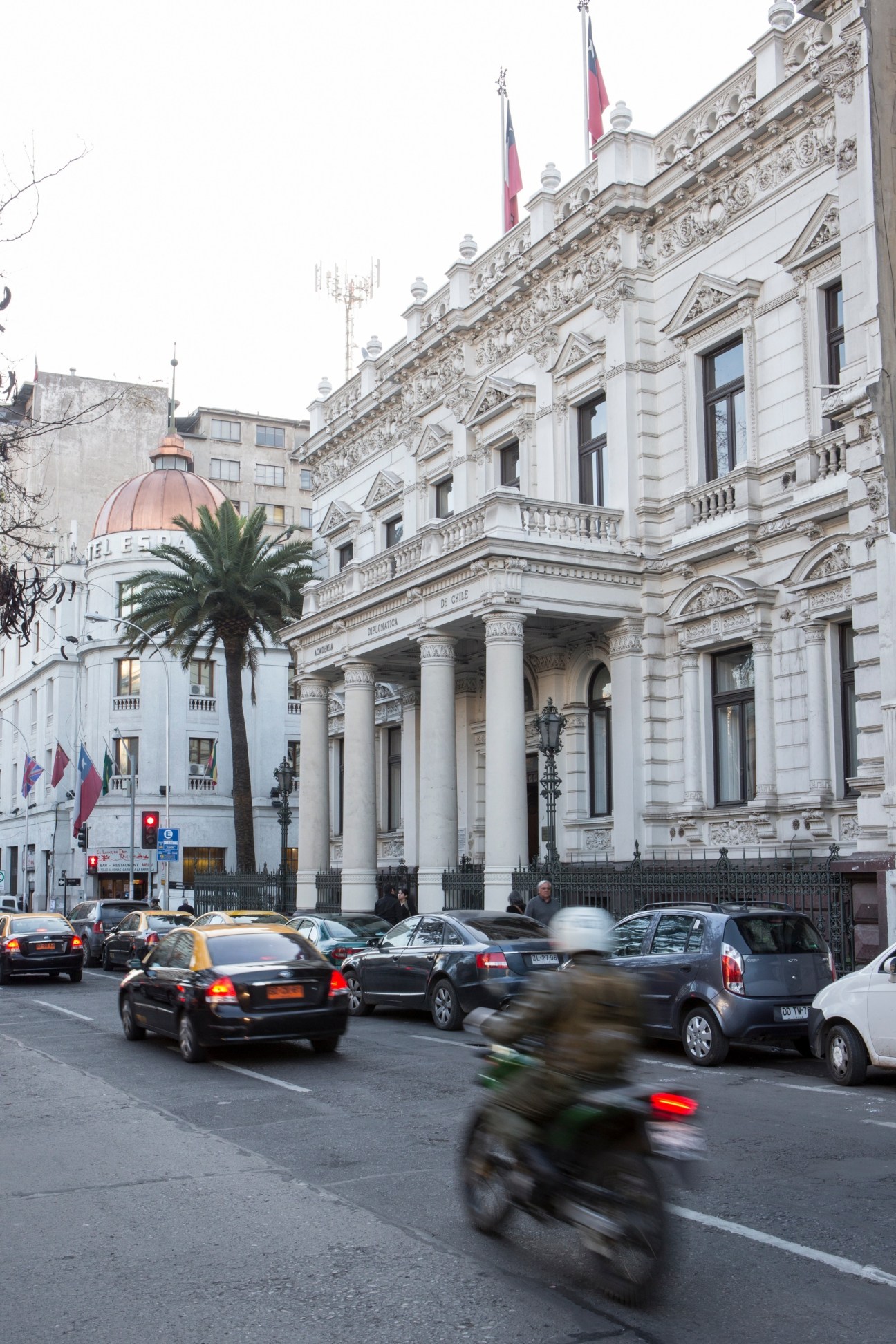 Neoclassical government building with ornate columns and Chilean flags on a Santiago street with traffic.