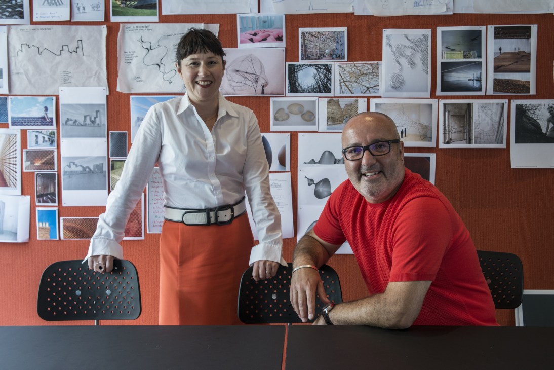 Peta Heffernan and Elvio Brianese of Liminal Studio in their Hobart office with design work pinned to a terracotta wall.
