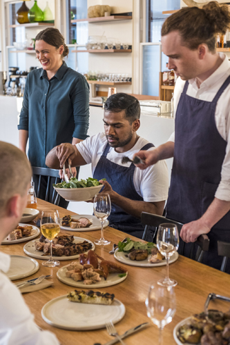 Staff members serve food during a communal meal at Agrarian Kitchen Eatery in Hobart.