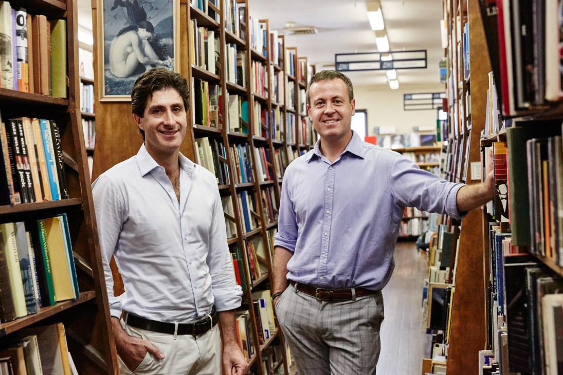 Two men stand between bookshelves in Berkelouw Bookshop's interior lined with books.