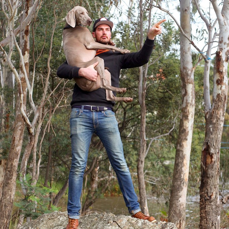 Tom Lillecrapp holds his German hunting dog Captain while standing in bushland.