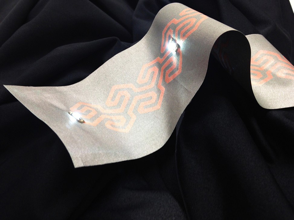 Cream-coloured fabric with orange circuit pattern and integrated soft circuitry technology.