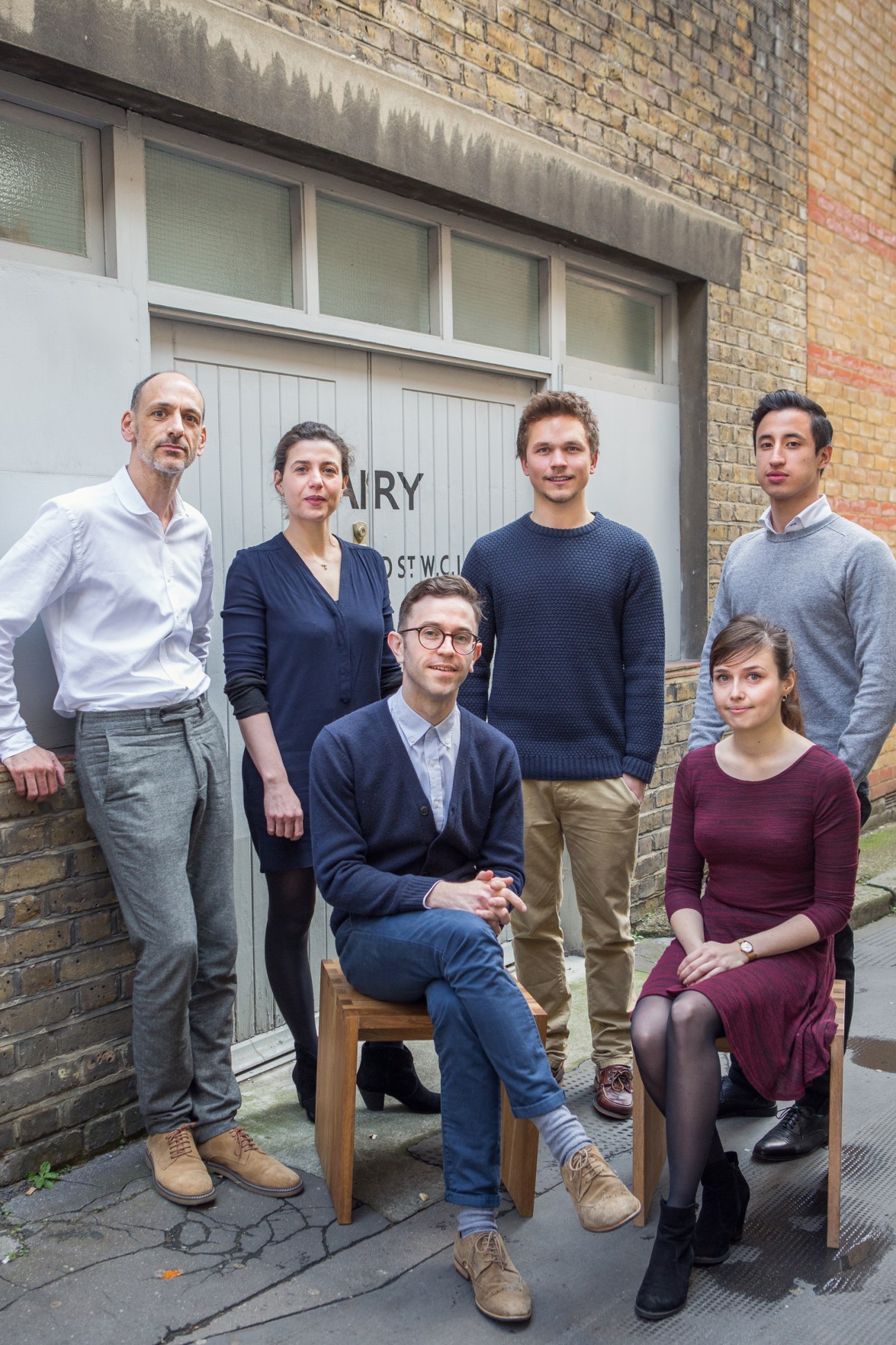 William Smalley and his architecture team pose outside a brick building entrance.