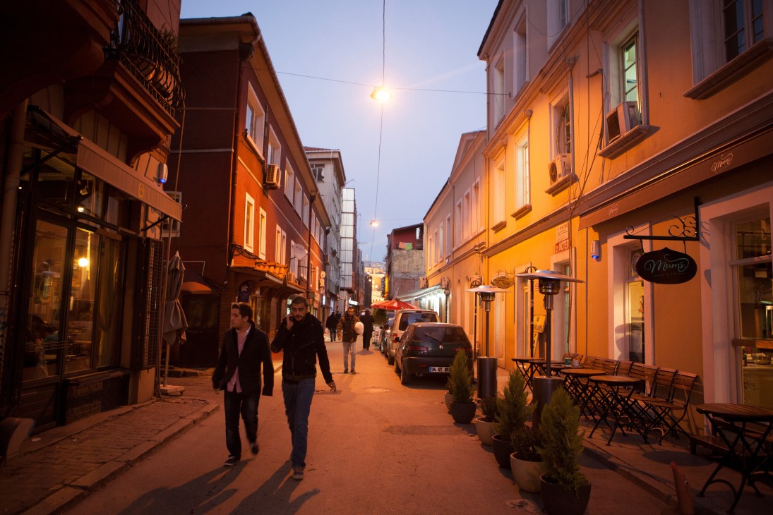 Evening street scene in Lisbon's Mouraria neighbourhood with illuminated buildings and pedestrians