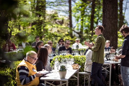 Guests dine at long tables outdoors among trees at the Lageder winery's Summa wine fair event.