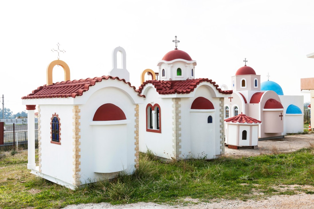 Prefabricated white churches with red domed roofs and crosses lined up in a row in Greece.