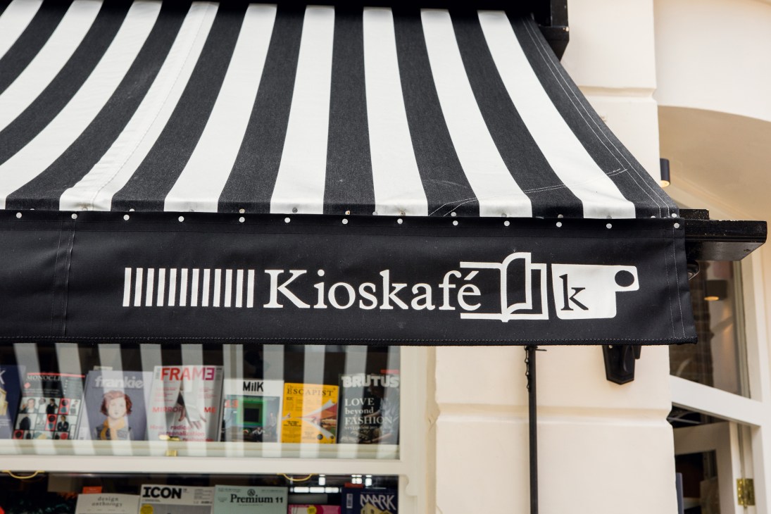 Kioskafé storefront with black and white striped awning and signage above window display.