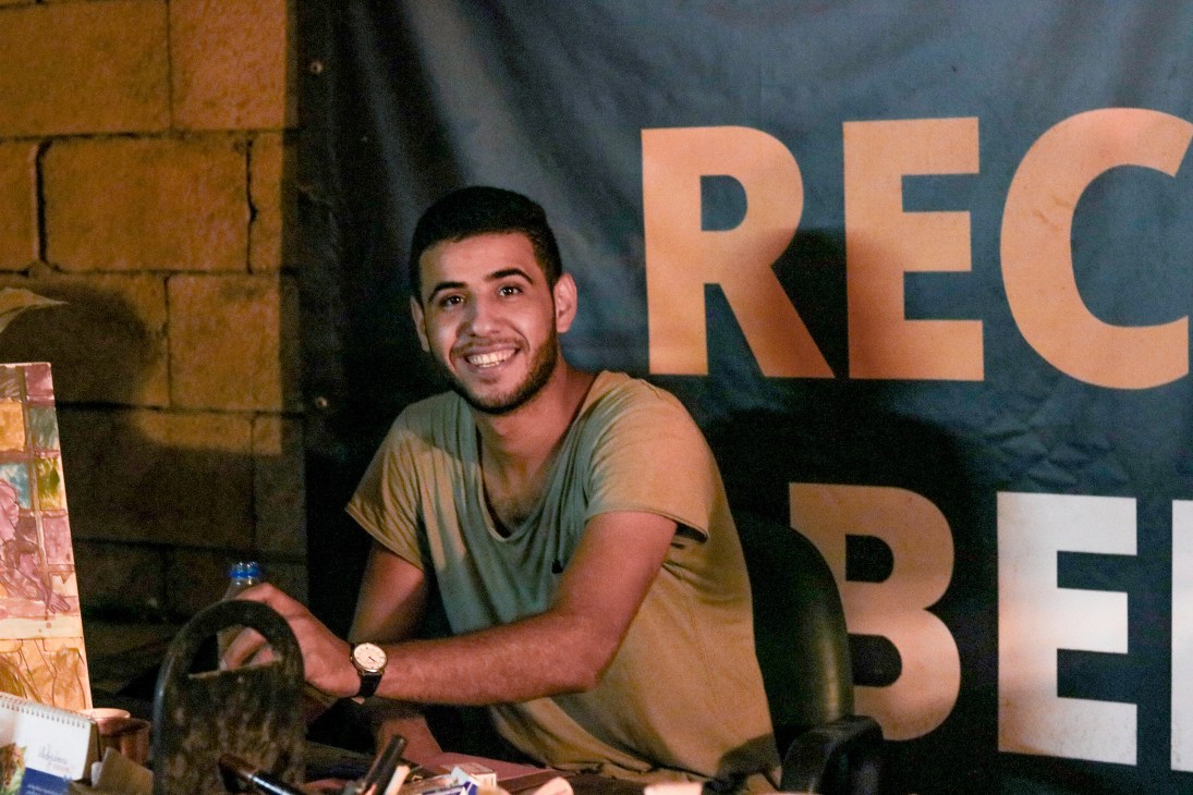 Sam Kazak, founder of Recycle Beirut, smiling at a table with recycled materials.